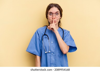 Young nurse caucasian woman isolated on yellow background keeping a secret or asking for silence.