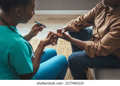 Young Nurse Doing A Glucose Blood Test On Her Senior Patient, During A Home Visit. Theme Diabetes. The Man Whose Glucose Was Measured By Going To The Home Of Healthcare Professionals.