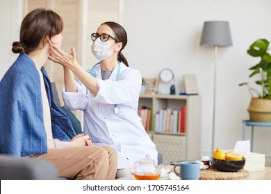 Young Nurse In Eyeglasses And In White Coat And Protective Mask Examining The Patient During The Visit At Home