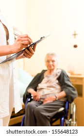 Young Nurse And Female Senior In Nursing Home, Measurements Are Taken Or Administrative Duties Taken Care Of