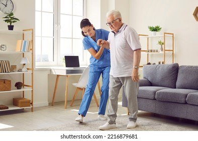 Young nurse helping elderly man walk in the room, holding his hand, supporting him. Treatment and rehabilitation after injury or stroke, life in assisted living facility, senior care concept - Shutterstock ID 2216879681