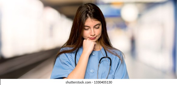 Young Nurse Looking Down With The Hand On The Chin In A Hospital