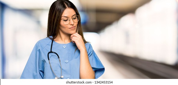 Young Nurse Looking Down With The Hand On The Chin In A Hospital