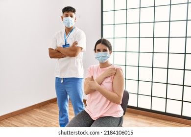 Young Nurse Man With Arms Crossed Gesture And Woman Patient Doing Ok Sign Showing Band Aid On Arm At The Clinic.