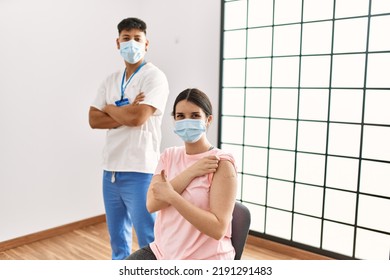 Young Nurse Man With Arms Crossed Gesture And Woman Patient Doing Ok Sign Showing Band Aid On Arm At The Clinic.