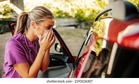 A Young Nurse Prepares For Her Shift At Work. A Nurse Dressed In Her Uniform Standing Outdoors In Front Of Her Car With A Mask On Her Face During The Day. 