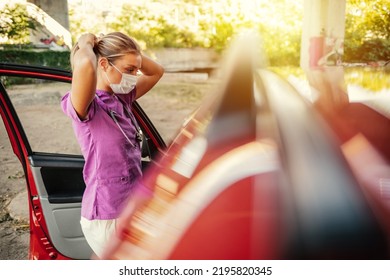 A Young Nurse Prepares For Her Shift At Work. A Nurse Dressed In Her Uniform Standing Outdoors In Front Of Her Car With A Mask On Her Face During The Day. 