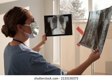 Young Nurse Or Radiologist Comparing Two X-ray Images Of Human Thorax After Medical Examination While Standing In Front Of Window