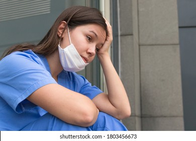 A Young Nurse Rests While Sitting Down, Sad Because Of The Difficult Situation At The Hospital.