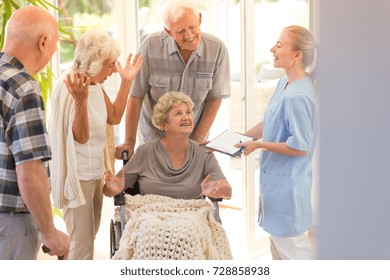 Young Nurse Saying Goodbye To Elder Woman Leaving Hospital With Her Siblings