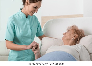 Young Nurse Supporting A Sick Old Woman In Hospital