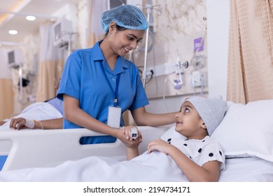 Young nurse visiting and consoling little girl lying on bed. Female child patient is looking at care giver while resting in ward. They are at healthcare center. - Powered by Shutterstock