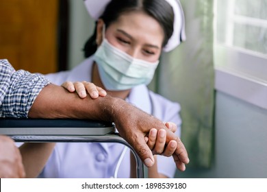 Young Nurse Woman Wearing Face Mask Taking Care Of Elderly Man Patient Sitting On Wheelchair In The Hospital, Nurse Holding A Patient's Hand, Close Up