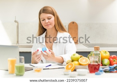 A young nutritionist is working at the table, studying the composition of vitamins.