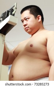 Young Obese Asian Man On The Weighing Scale