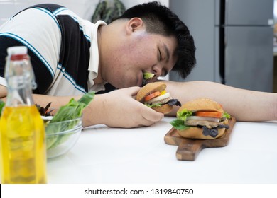 Young Obese Man Sleeping While Eating And Holding Hamburger In His Hand