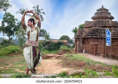 Young odissi dancer striking pose in front of Sukasari temple with sculptures in bhubaneswar, odisha, India. Indian Culture