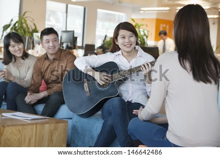 Young Office Worker Playing Guitar to Colleagues