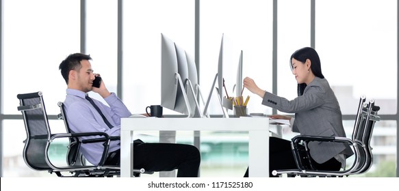 Young Office Workers Are Dedicated To Working Hard In Modern Office. Man Is Calling While Woman Woking.