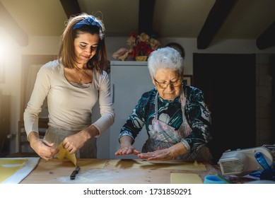 Young And Old Woman Cooking Together Traditional Recipes As Homemade Fresh Pasta.