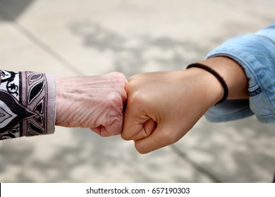 Young And Old Woman Are Fist Bumping, Young And Old Ethnic Contest 