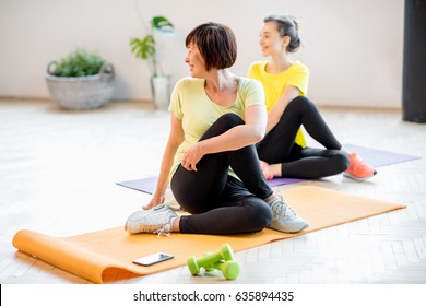 Young And Older Women In Sports Wear Doing Yoga Together Indoors At Home Or A Gym