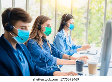 Young Operator Women And Man Call Center Wear Headset And Medical Mask Working  Consulting Customers With Online Problems. They Work With Social Distance In New Normal Concept.