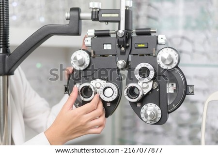 Young ophthalmologist doing visual test for customer using Bifocal Optometry eyesight measurement device in optical center, eyecare concept.