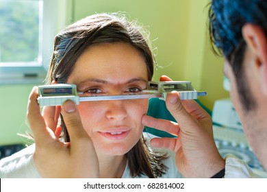 A Young Ophthalmologist Using An Exophthalmometer, An Instrument Used For Measuring The Degree Of Forward Displacement Of The Eye In Exophthalmos