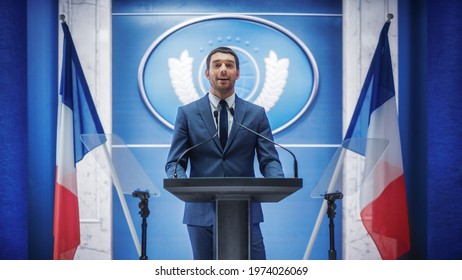 Young Organization Representative Speaking At Press Conference In Government Building. Press Officer Delivering A Speech At Summit. Minister Speaking To Congress. Backdrop With French Flags.