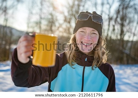 Young outdoor woman drinks a cup of hot tea in snowy wintertime, Czech Republic, Europe