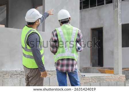Young overweight engineering foreman reading blueprint paperwork on construction site outdoors with Asian or Indian contractor man partnership project manager using laptop technology solving problem