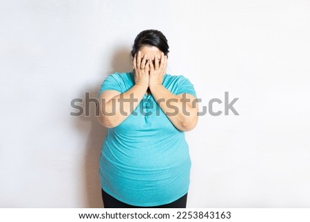 Young overweight indian woman covering eyes with hands feeling embarrassed, Plus size asian female with sad and fear expression. Body Shaming and obesity concept.