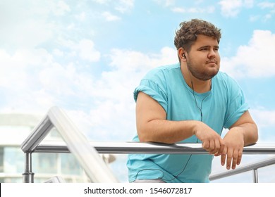 Young overweight man leaning on railing outdoors