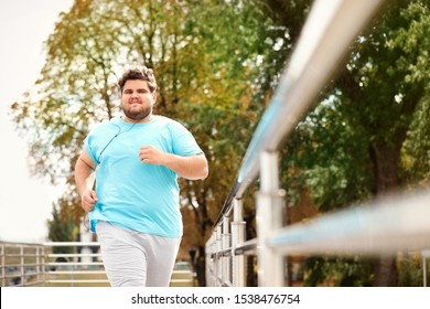 Young overweight man running outdoors. Fitness lifestyle