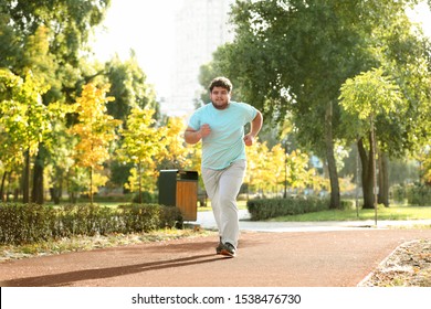 Young overweight man running in park on sunny day