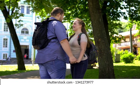 Young overweight man and woman holding hands and looking at each other with love