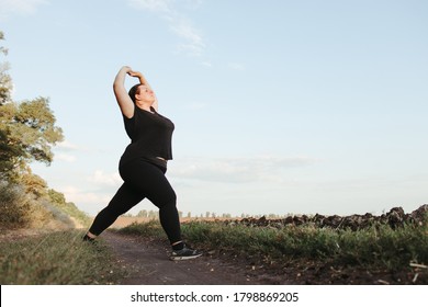 Young overweight woman doing morning yoga on the country road, open air activity. Healthy lifestyle, sport, weight loss - Powered by Shutterstock