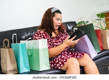 Young Overweight Woman Sitting Among Shopping Bags. Girl Get Shock When She Open Her Wallet After Shopping Online. Concept Compulsive Shopping.Retail Therapy Addiction. Financial Discipline.