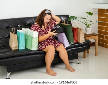 Young Overweight Woman Sitting Among Shopping Bags. Girl Get Shock When She Open Her Wallet After Shopping Online. Concept Compulsive Shopping.Retail Therapy Addiction. Financial Discipline.