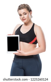 Young Overweight Woman In Sportswear Holding Digital Tablet And Looking At Camera Isolated On White 