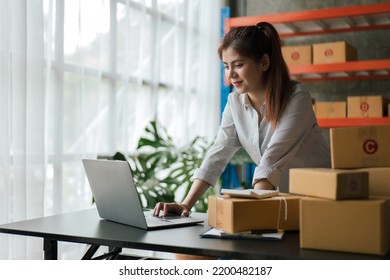Young owner business woman received orders clients and products in parcel cardboard box packaging on the rack in warehouse. - Shutterstock ID 2200482187