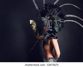 Young Pagan Priest In Ritual Suit With Green Iguana In His Hands. Photo.