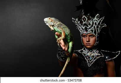 Young Pagan Priest In Ritual Suit With Green Iguana In His Hands. Photo.