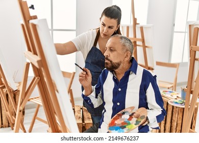 Young painting teacher woman teaching art to senior man painting on canvas at art studio - Powered by Shutterstock