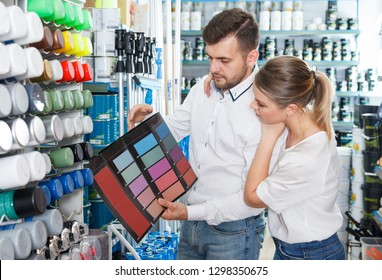 Young Pair Choosing Color For Painting Using Palette Scheme In Paint Store 