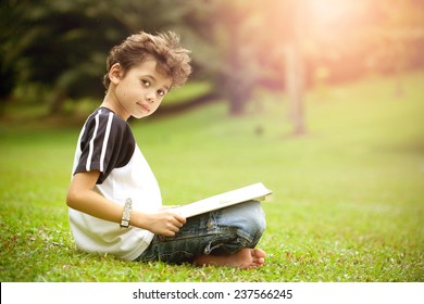 Young Pan Asian Boy Enjoying His Reading Book In Outdoor Park