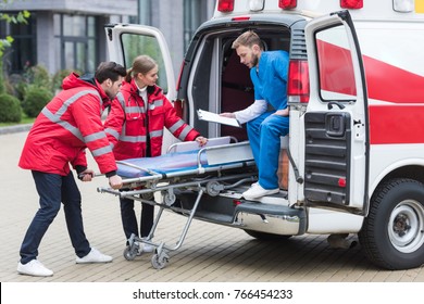 young paramedics moving out ambulance stretcher from car - Powered by Shutterstock