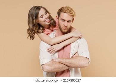 Young Parent Man Have Fun With Child Teen Girl Wear Casual Pastel Clothes Dad Little Kid Daughter Hug Stand Behind Kidding Show Tongue Isolated On Beige Background Father's Day Love Family Concept.