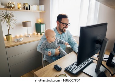 Young parent working from home while holding his baby boy on his lap while they both watch to the screen. - Powered by Shutterstock